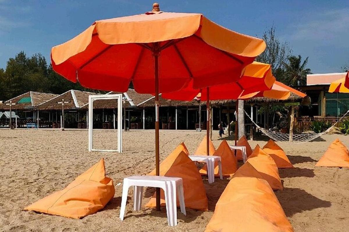 písečná pláž s oranžovými slunečníky a lehátky