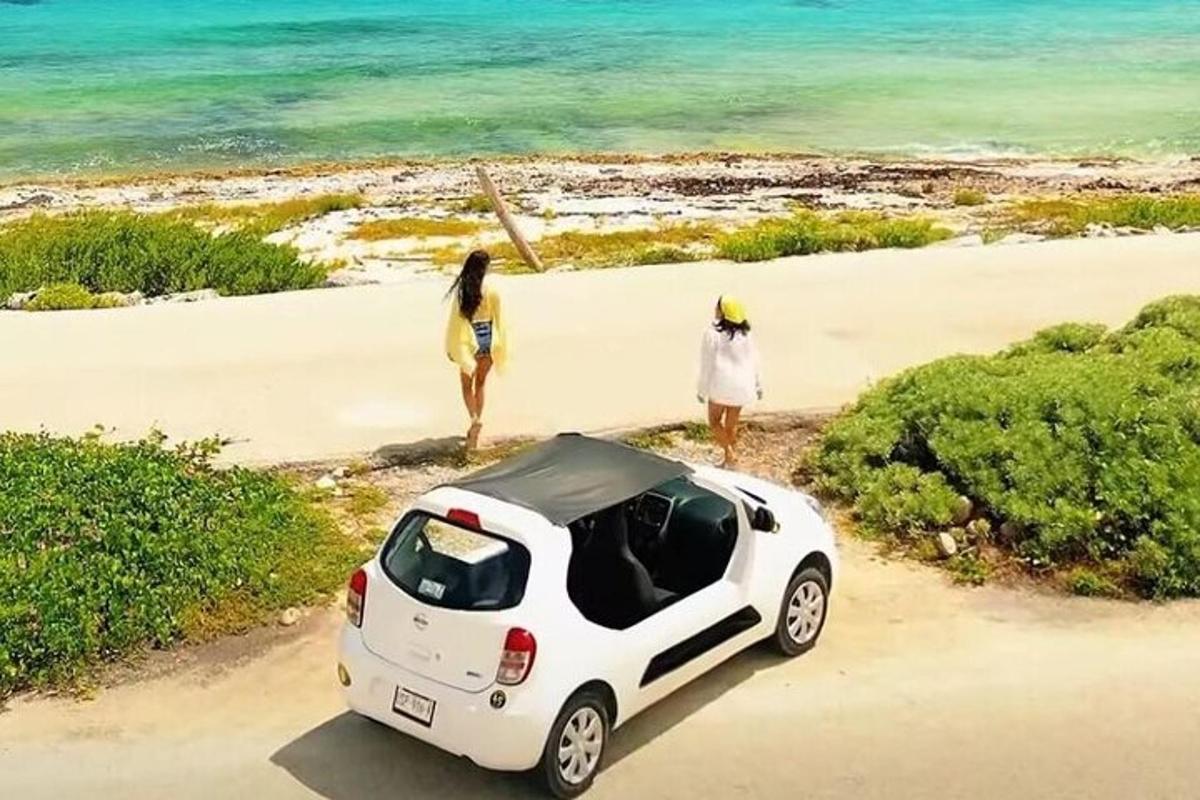 due donne in piedi accanto a un'auto bianca sulla spiaggia