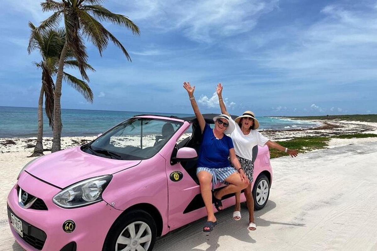 due donne sedute in un'auto rosa sulla spiaggia