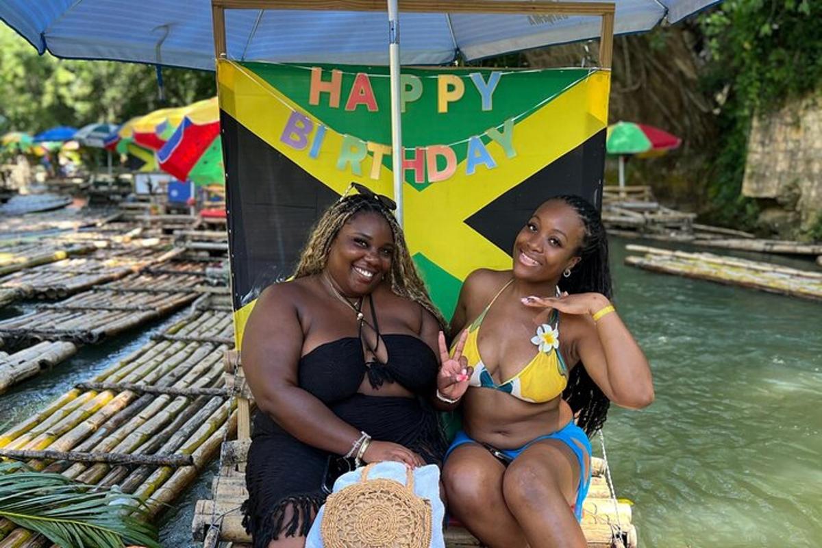 due donne in costume da bagno sedute accanto a un cartello di buon compleanno
