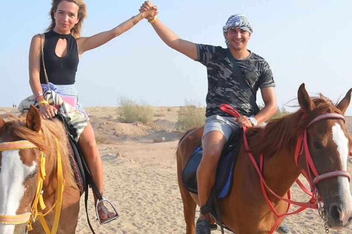 zwei Personen reiten auf einem Pferd in der Wüste