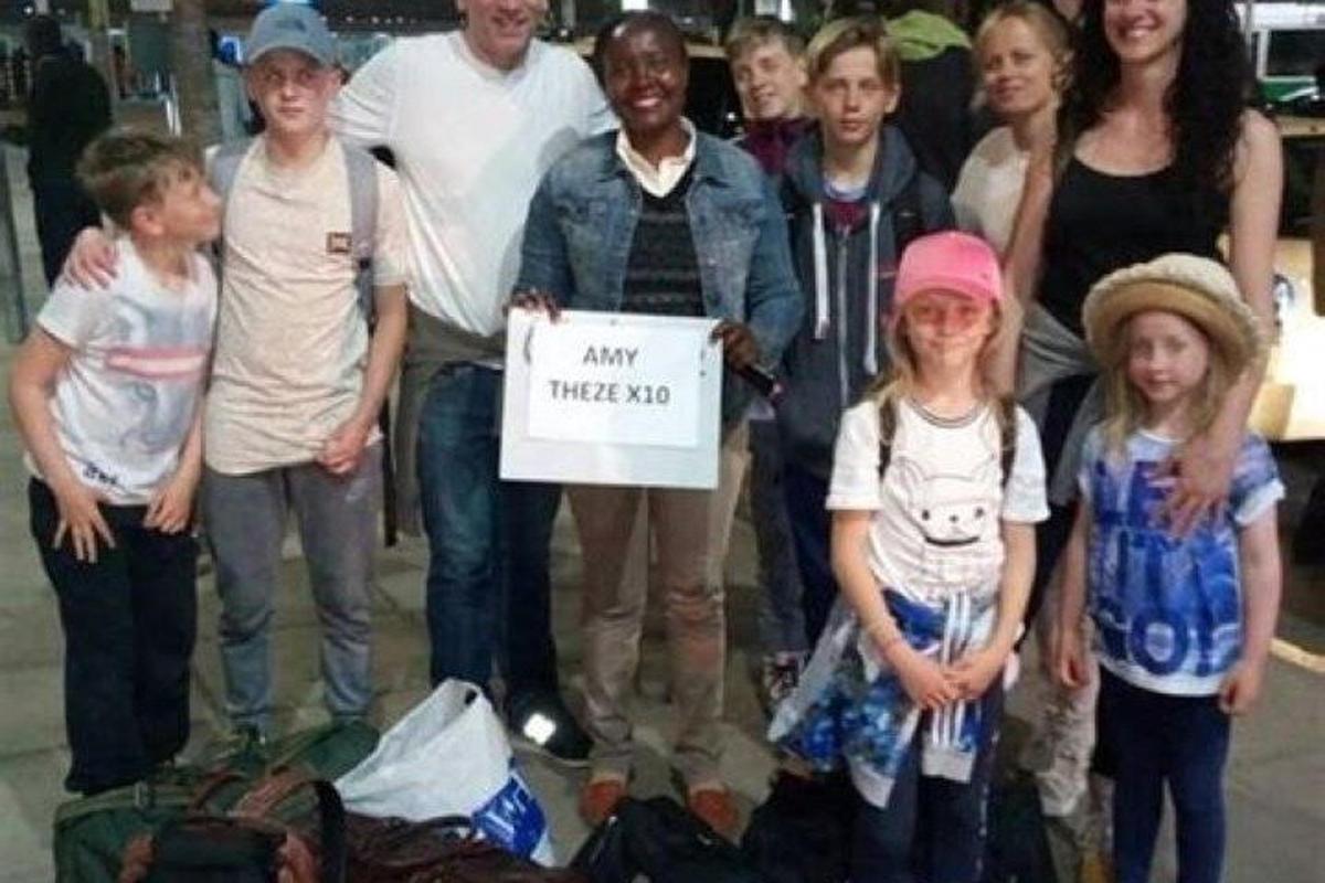 a group of people posing for a picture with a sign
