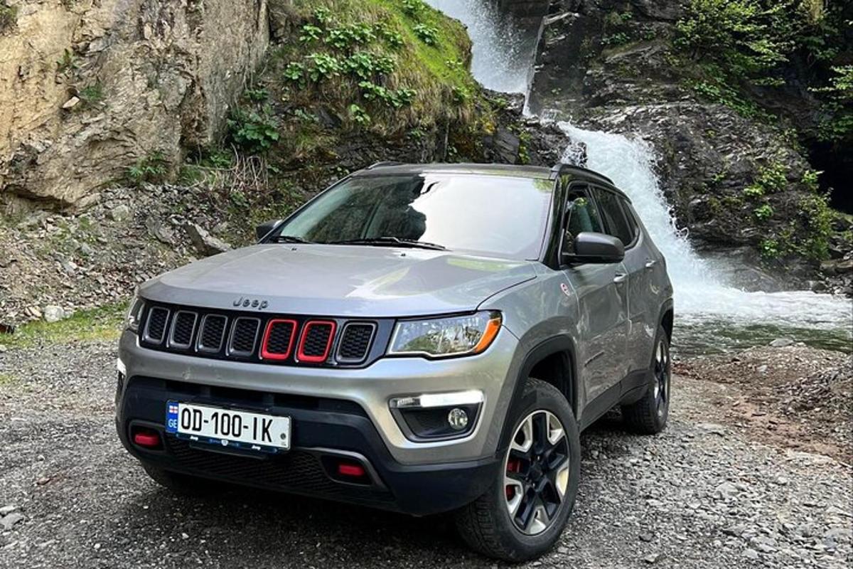 een grijze jeep geparkeerd voor een waterval