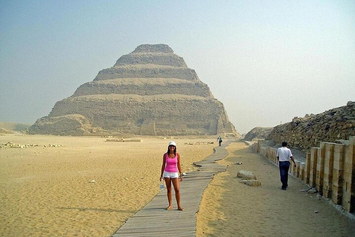 una donna che cammina su una passerella di fronte alla piramide