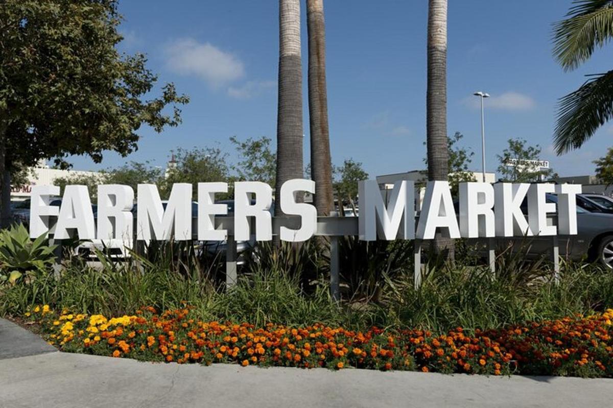 uma placa para um mercado de agricultores com flores e palmeiras
