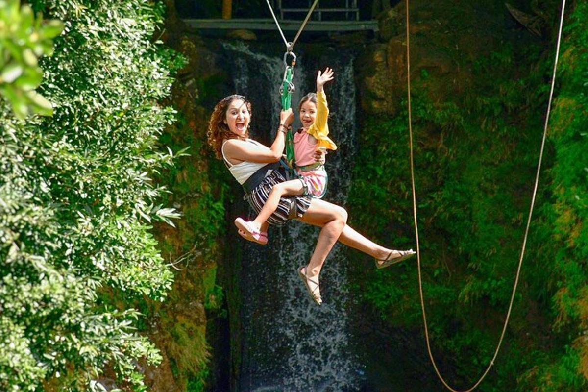 una dona i una nena muntades en un gronxador de corda sobre una cascada