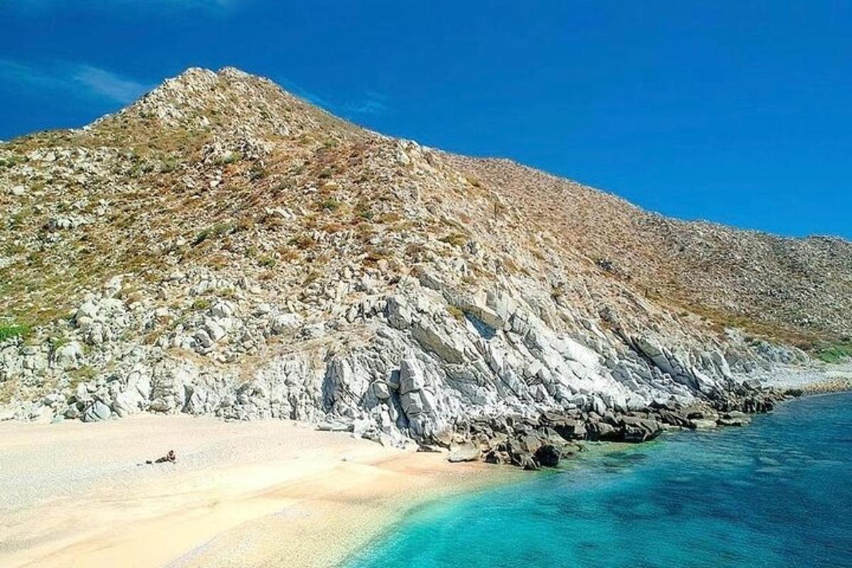 uma praia com uma montanha rochosa e o oceano
