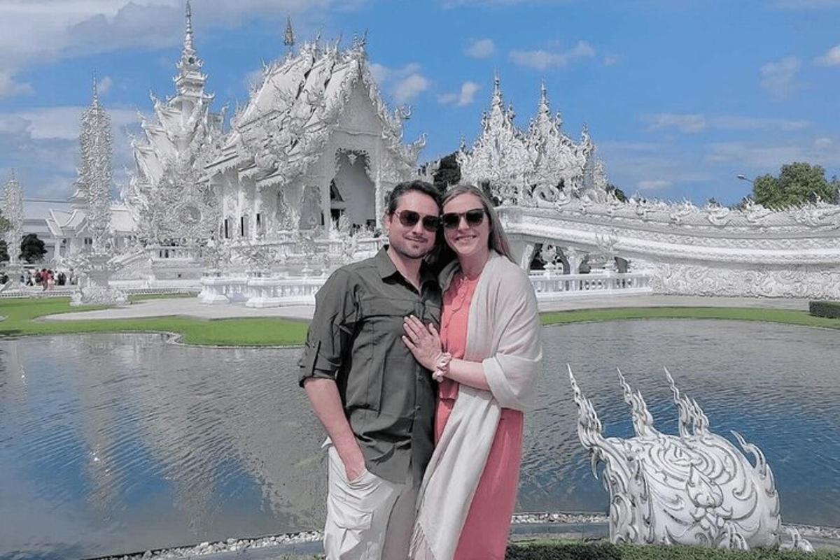 a man and woman posing in front of a white temple