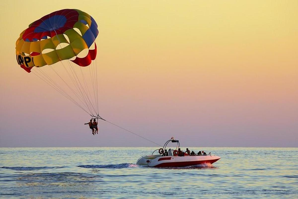 a group of people on a boat in the water with a parachute