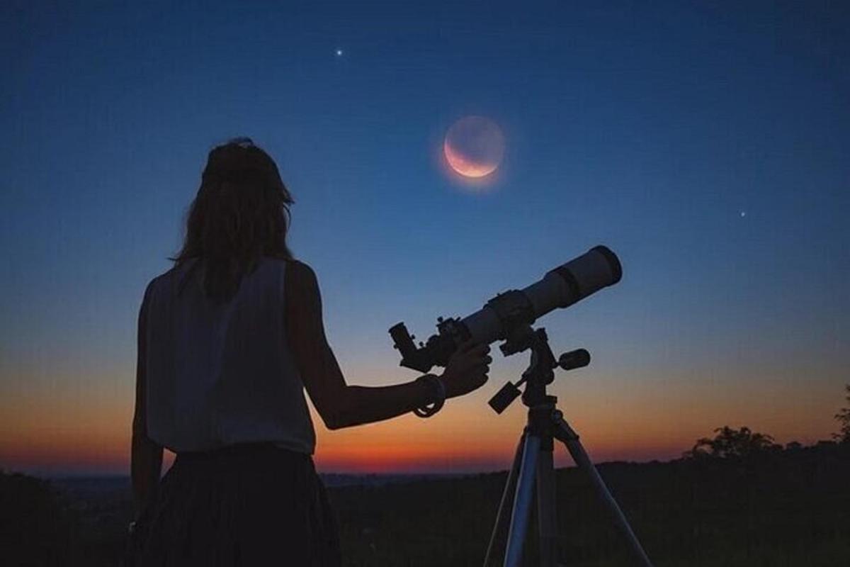 una donna che guarda la luna attraverso un telescopio