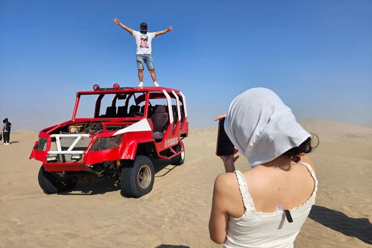 אישה עומדת על גגות ג'יפ אדום במדבר