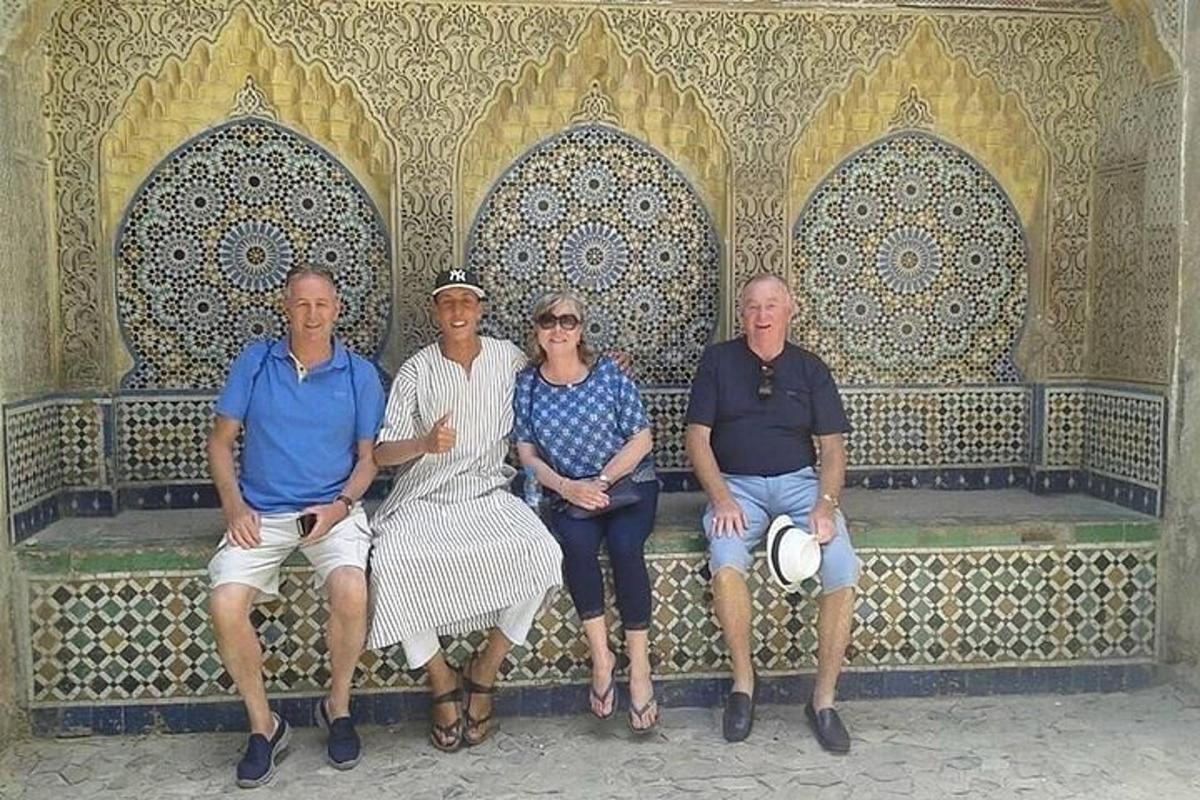 hópur fólks situr á bekk fyrir framan byggingu