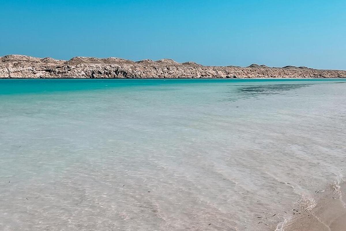 egy strand tiszta vízzel és sziklákkal a háttérben