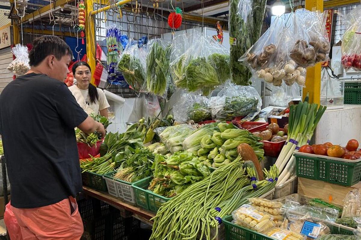 Un hombre parado en un mercado con una pila de verduras