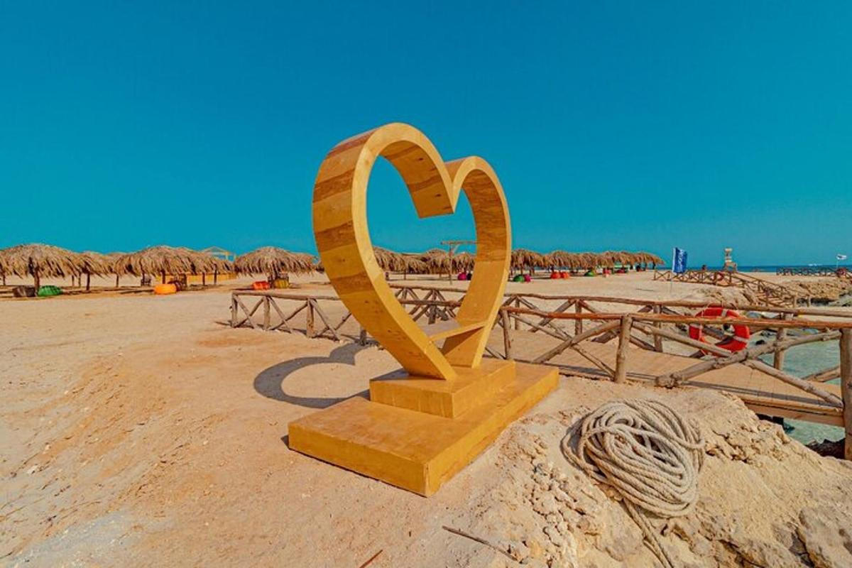 una estàtua de cor d'or en una platja de sorra