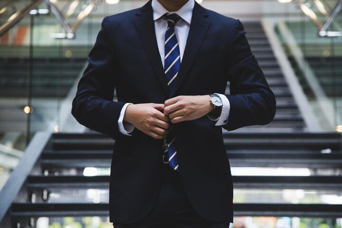 a man in a suit and tie with his hands