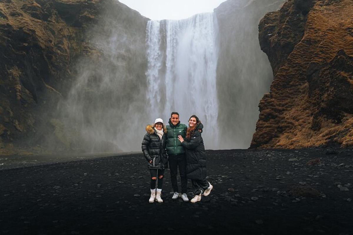 tiga orang berdiri di depan air terjun