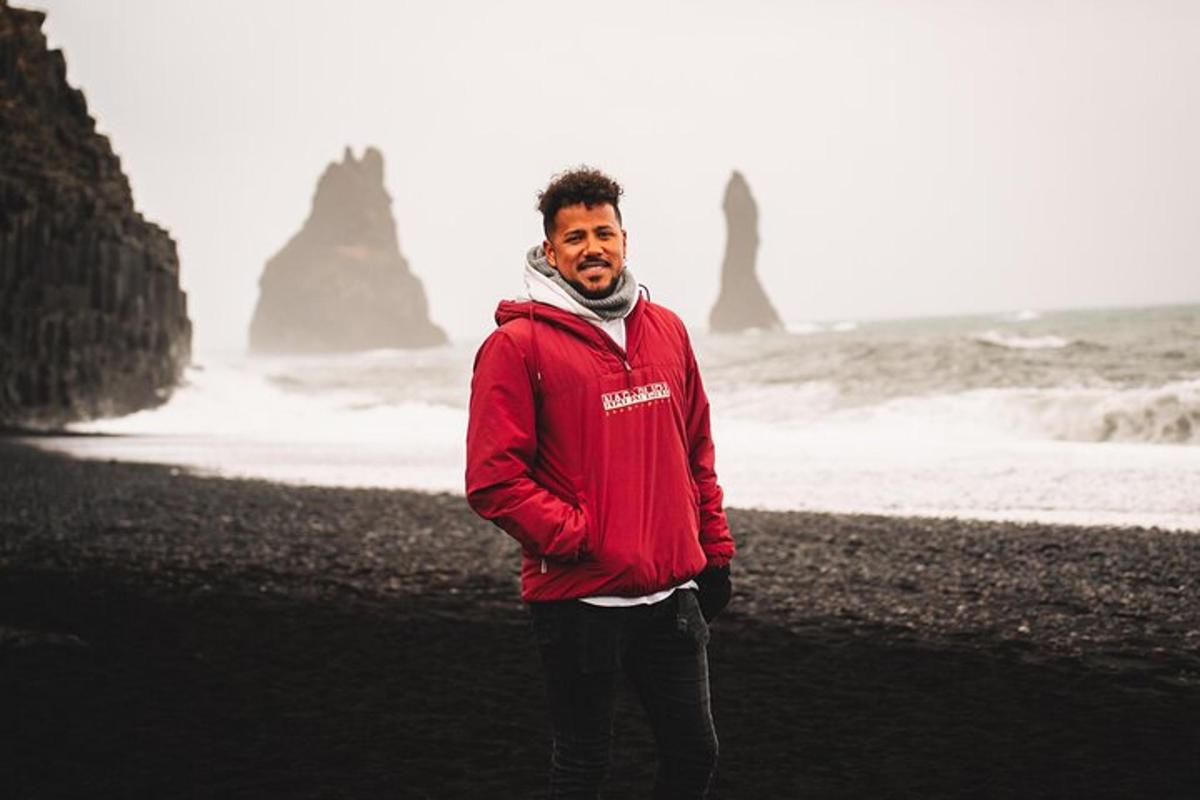 seorang pria berjaket merah berdiri di pantai