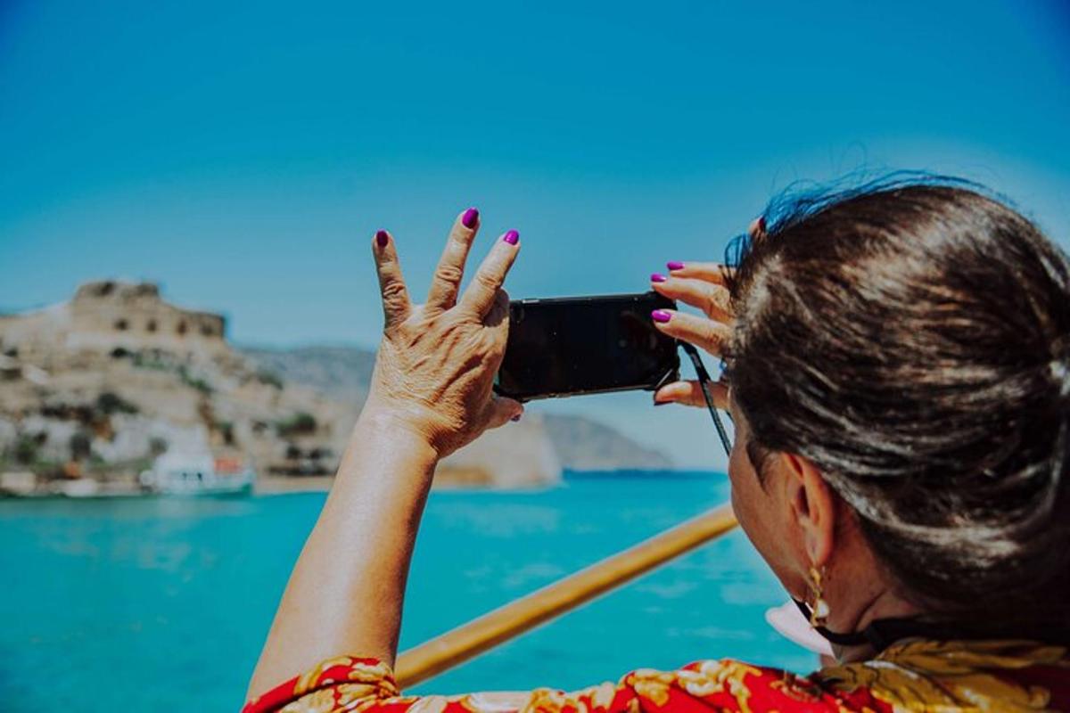 Una mujer tomando una fotografía del océano con su teléfono celular.