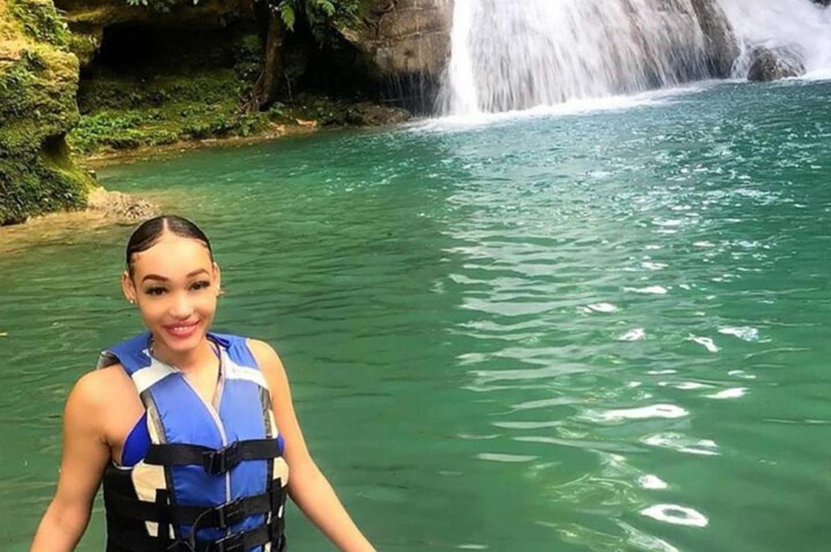 a woman standing in the water in front of a waterfall
