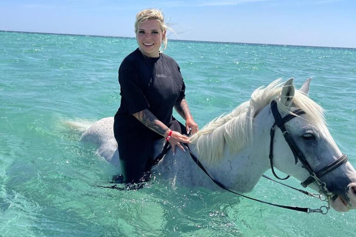 eine Frau, die auf einem Pferd im Meer steht