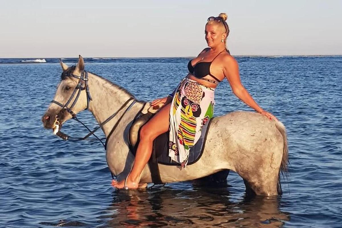 a woman sitting on a horse in the water