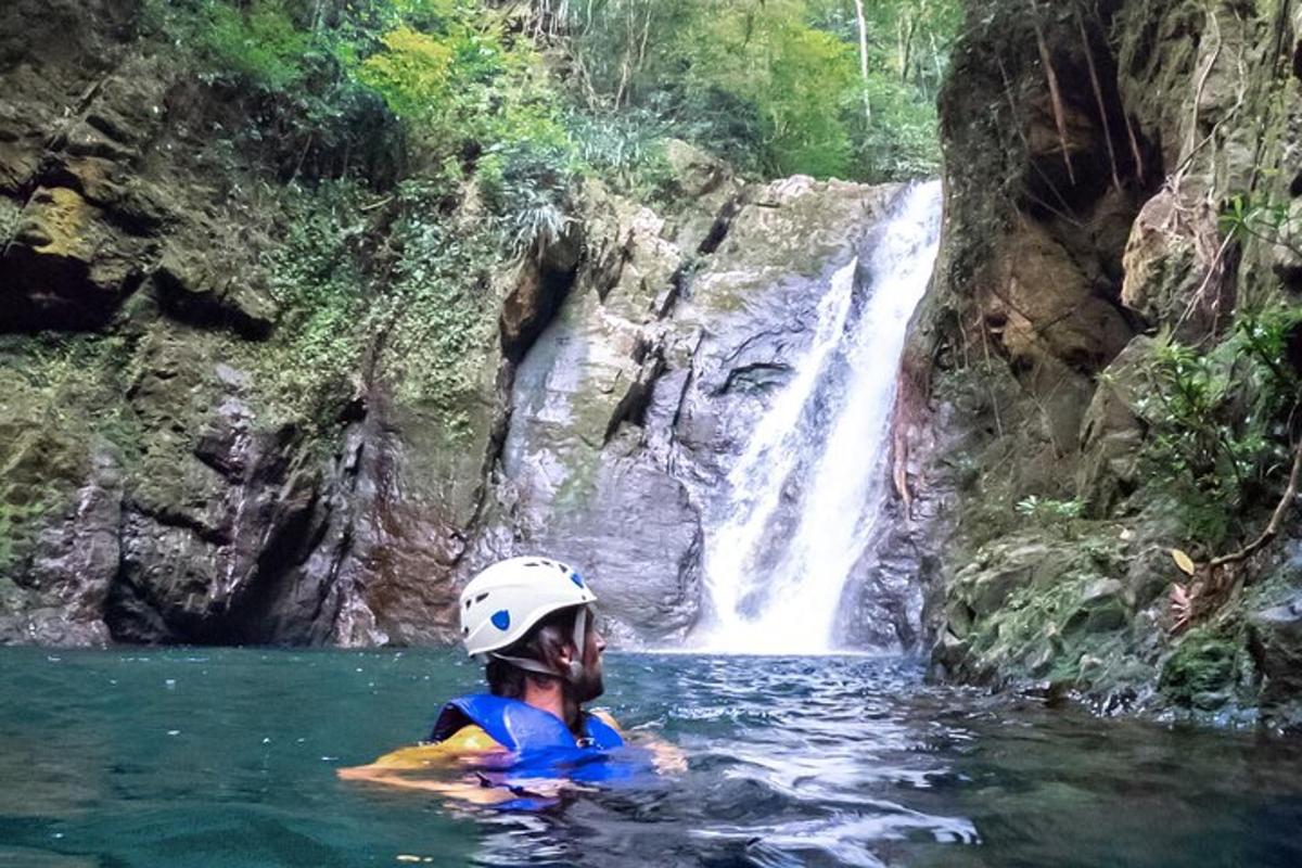 a man in the water in front of a waterfall