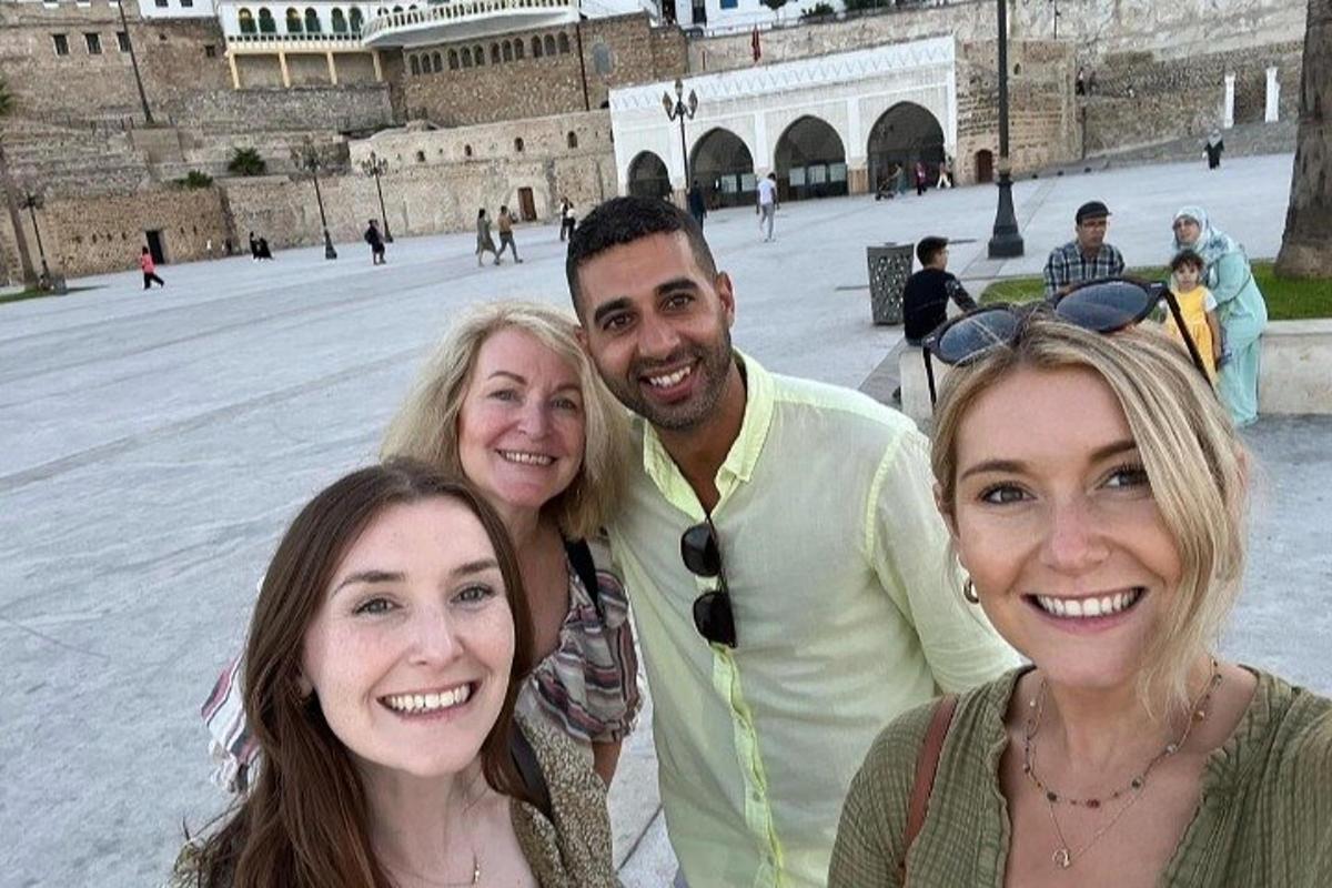 bir binanın önünde fotoğraf çektiren bir erkek ve üç kadın