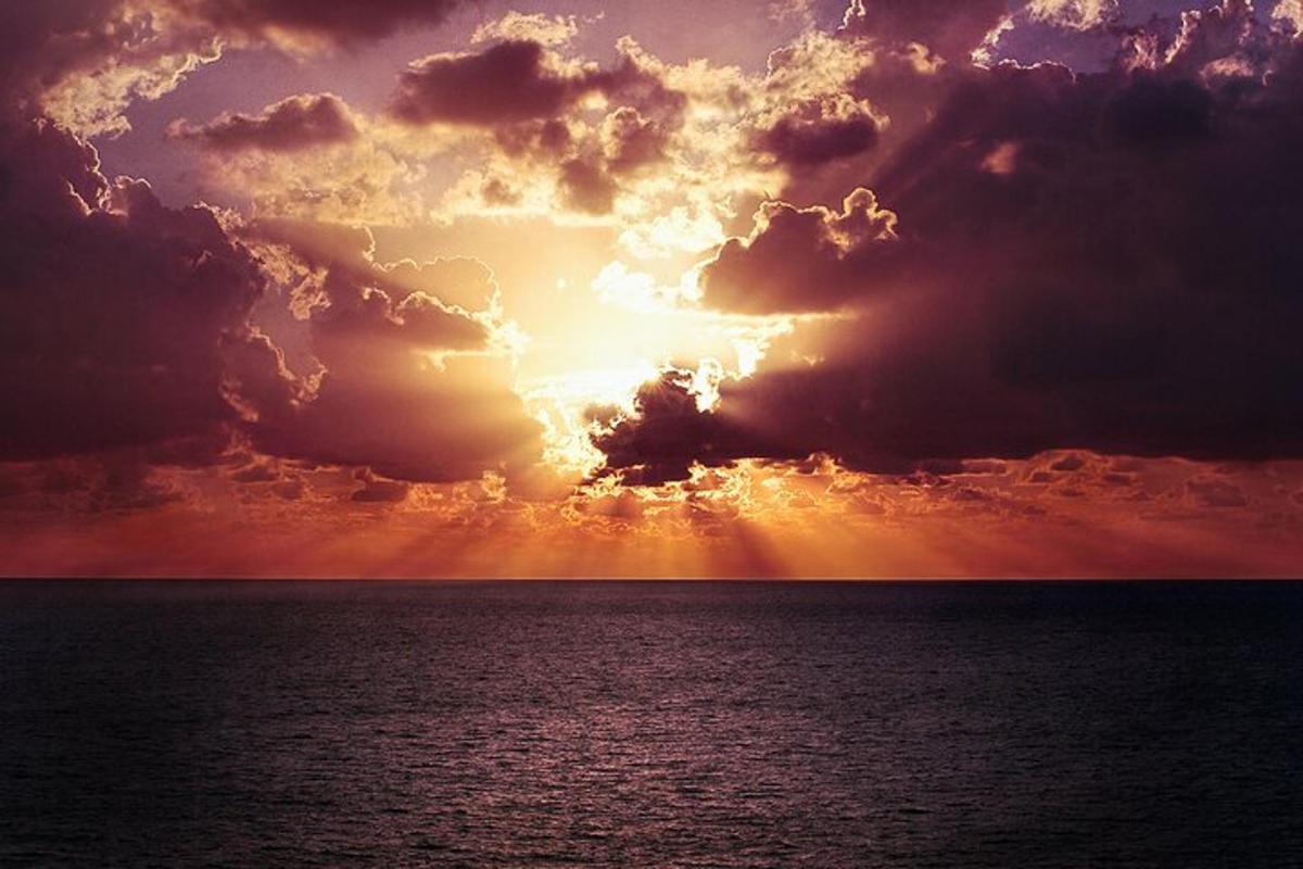 un tramonto sull'oceano sotto un cielo nuvoloso