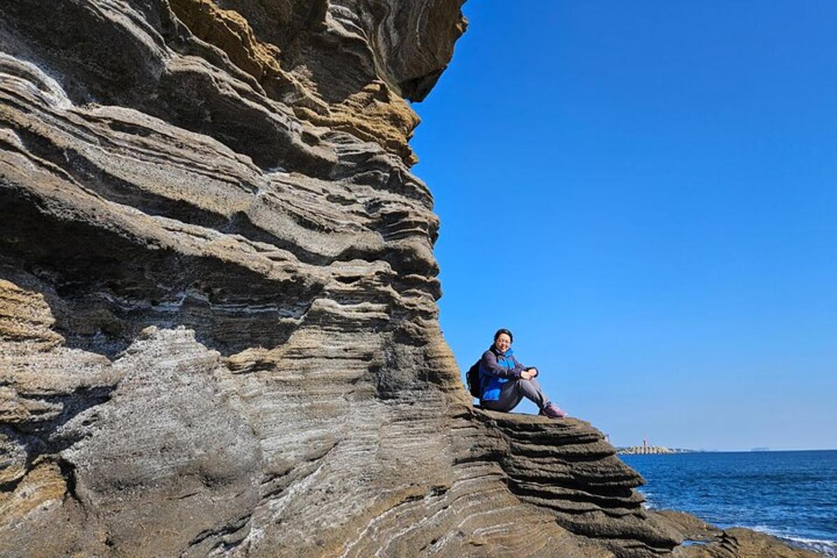 žena sedící na skále poblíž oceánu