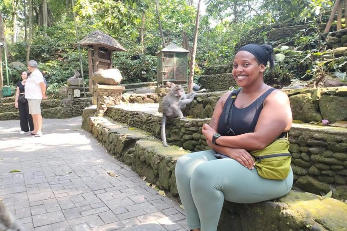 uma mulher sentada em um muro de pedra em frente a um macaco