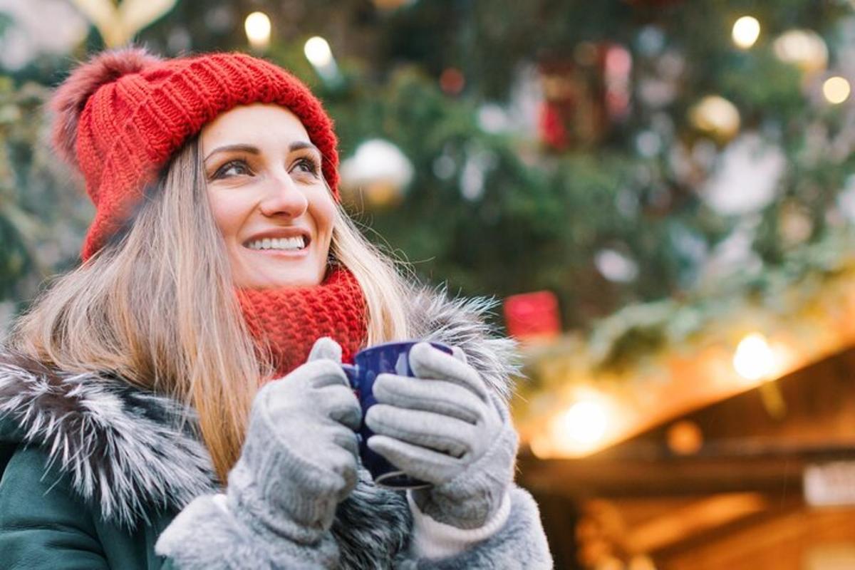 a woman holding a coffee cup in front of a christmas tree