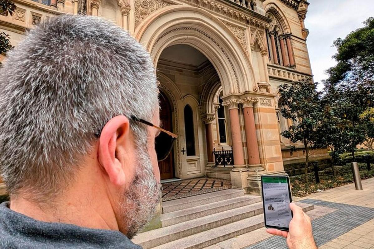 moški gleda v svoj mobilni telefon pred stavbo