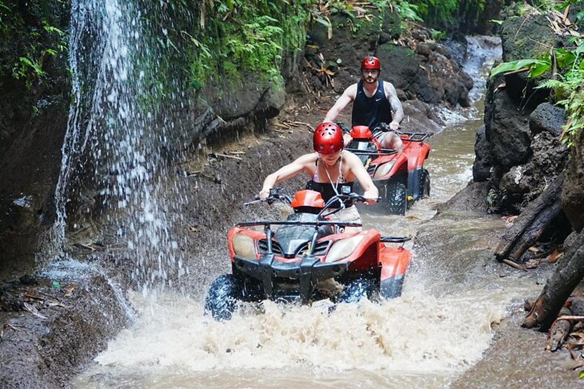 two people riding on atvs through a waterfall