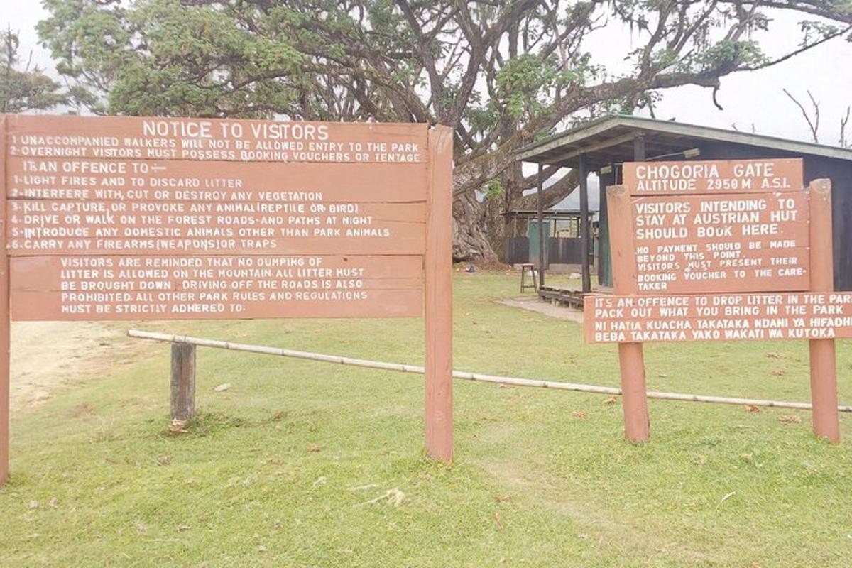 a sign in front of a park with a building