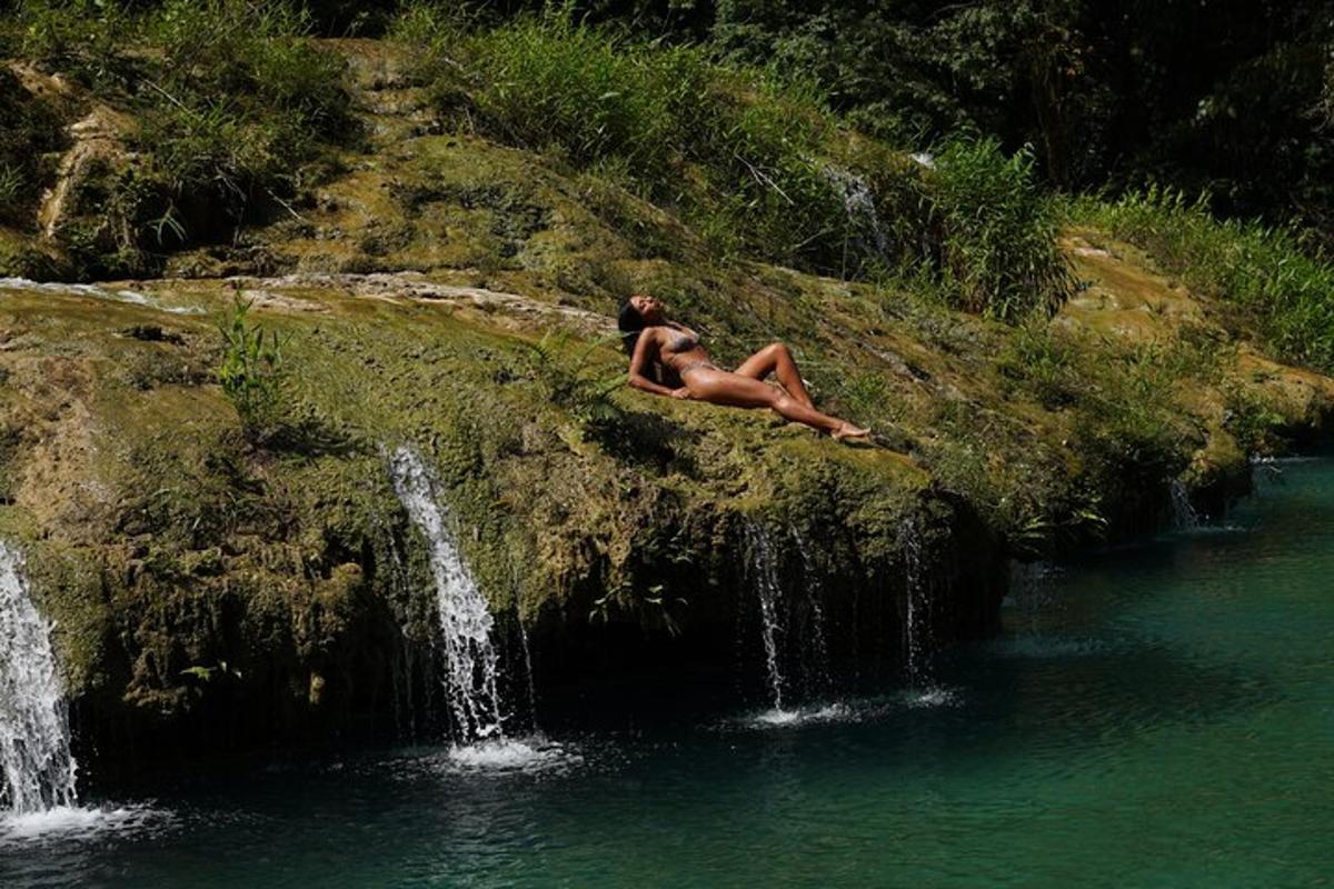a woman sitting on the side of a waterfall