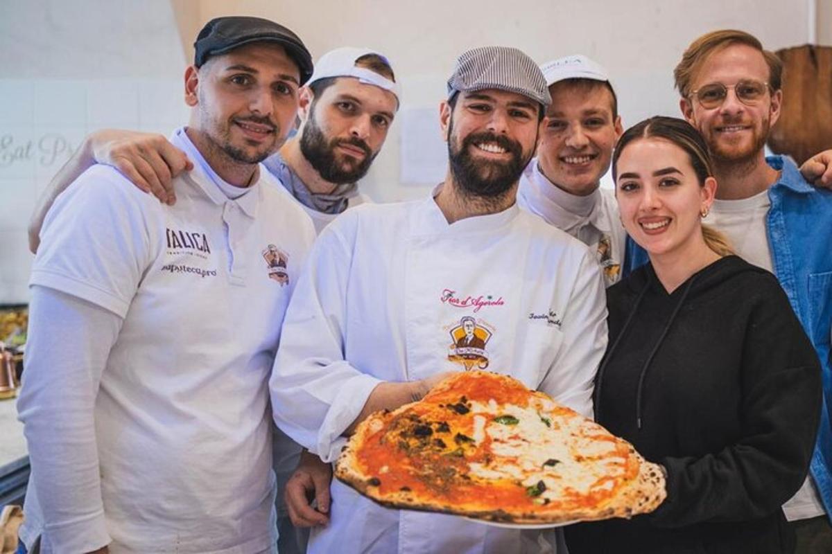 žena držící pizzu se skupinou kuchařů