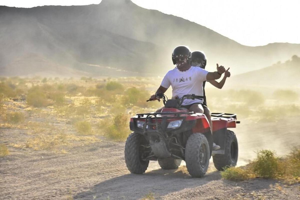 due persone in sella a un quad su una strada sterrata