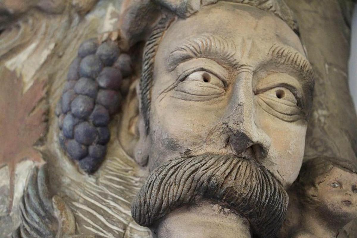 une statue d'un homme avec des raisins et une barbe