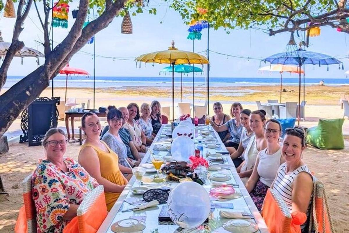 un gruppo di persone sedute a un lungo tavolo sulla spiaggia