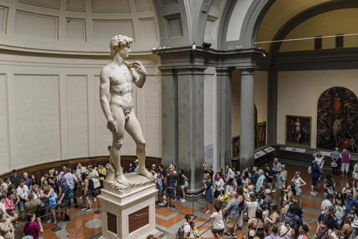 Una multitud de personas de pie alrededor de una estatua en un museo.