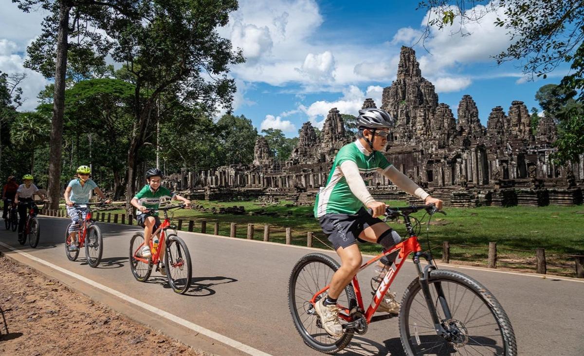 three people riding bikes down a road in front of temples