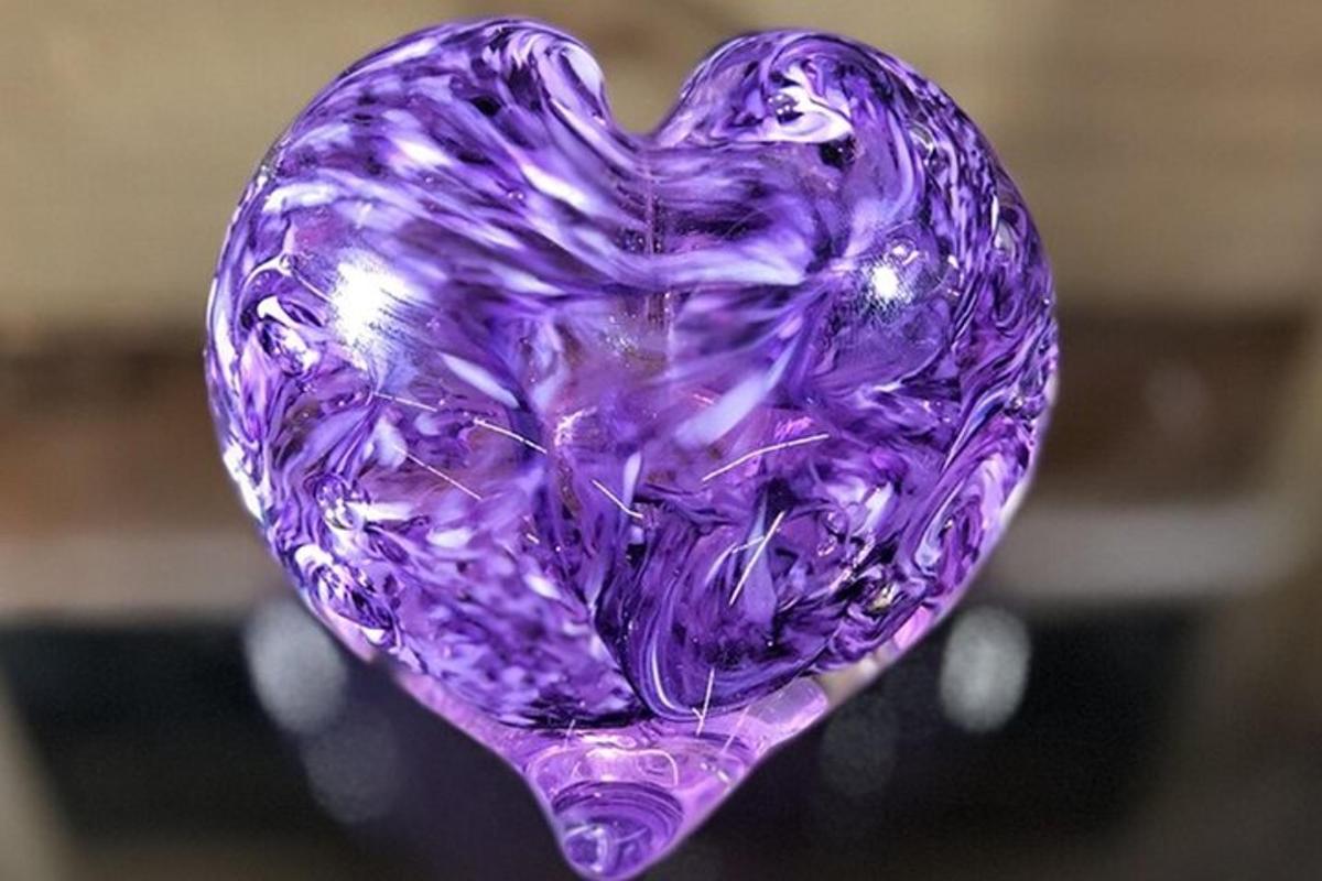 um vaso de vidro roxo em forma de coração sobre uma mesa
