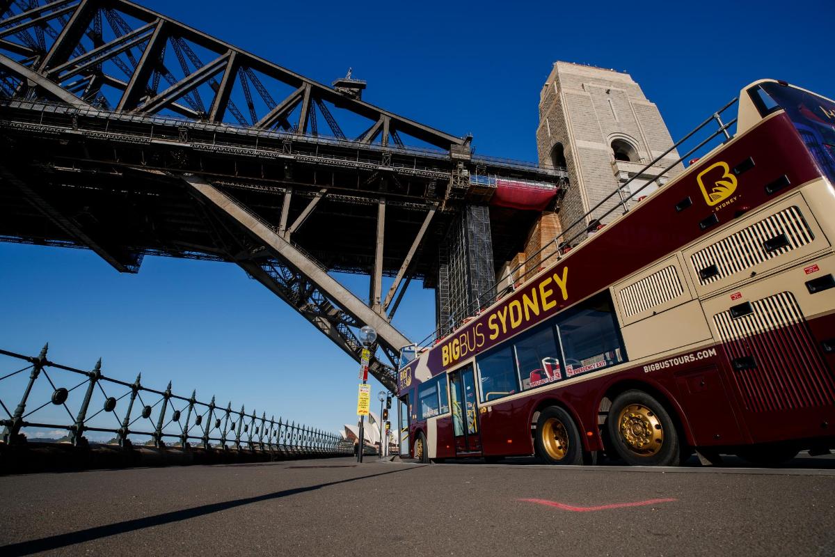 a double decker bus driving under a bridge