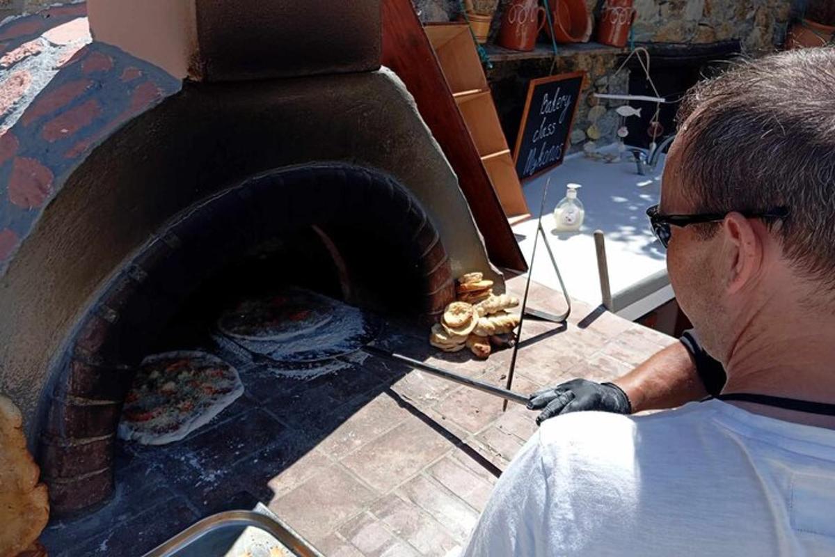 mężczyzna wkłada jedzenie do pieca do pizzy