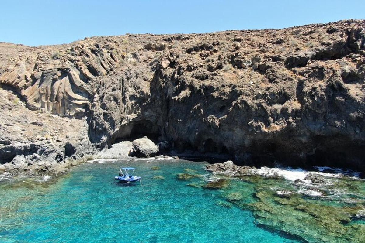 a boat in a body of water next to a cliff
