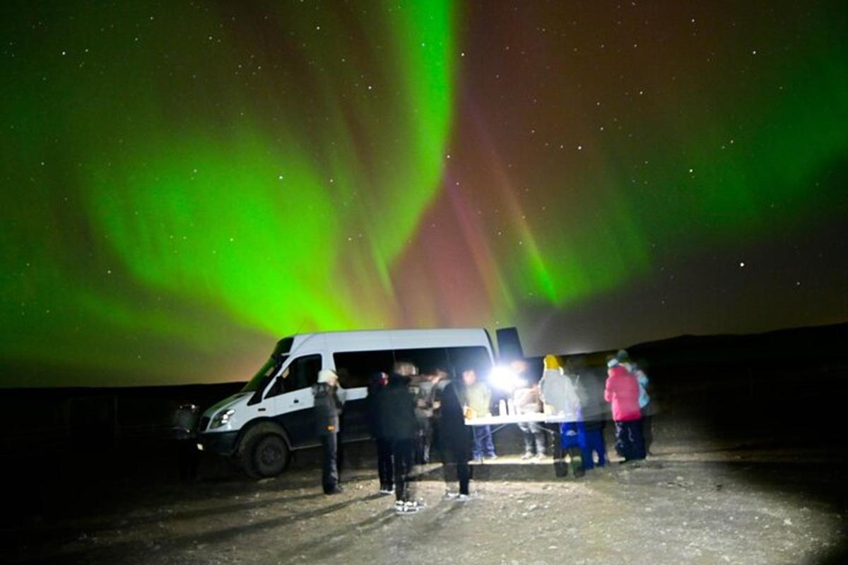 un gruppo di persone in piedi davanti a un furgone sotto l'aurora