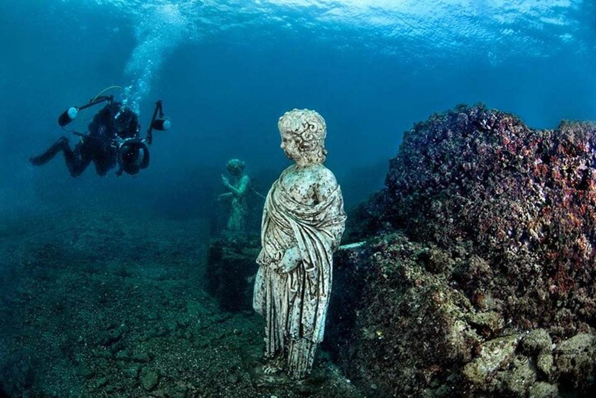 ένα άτομο που φωτογραφίζει ένα άγαλμα στον ωκεανό