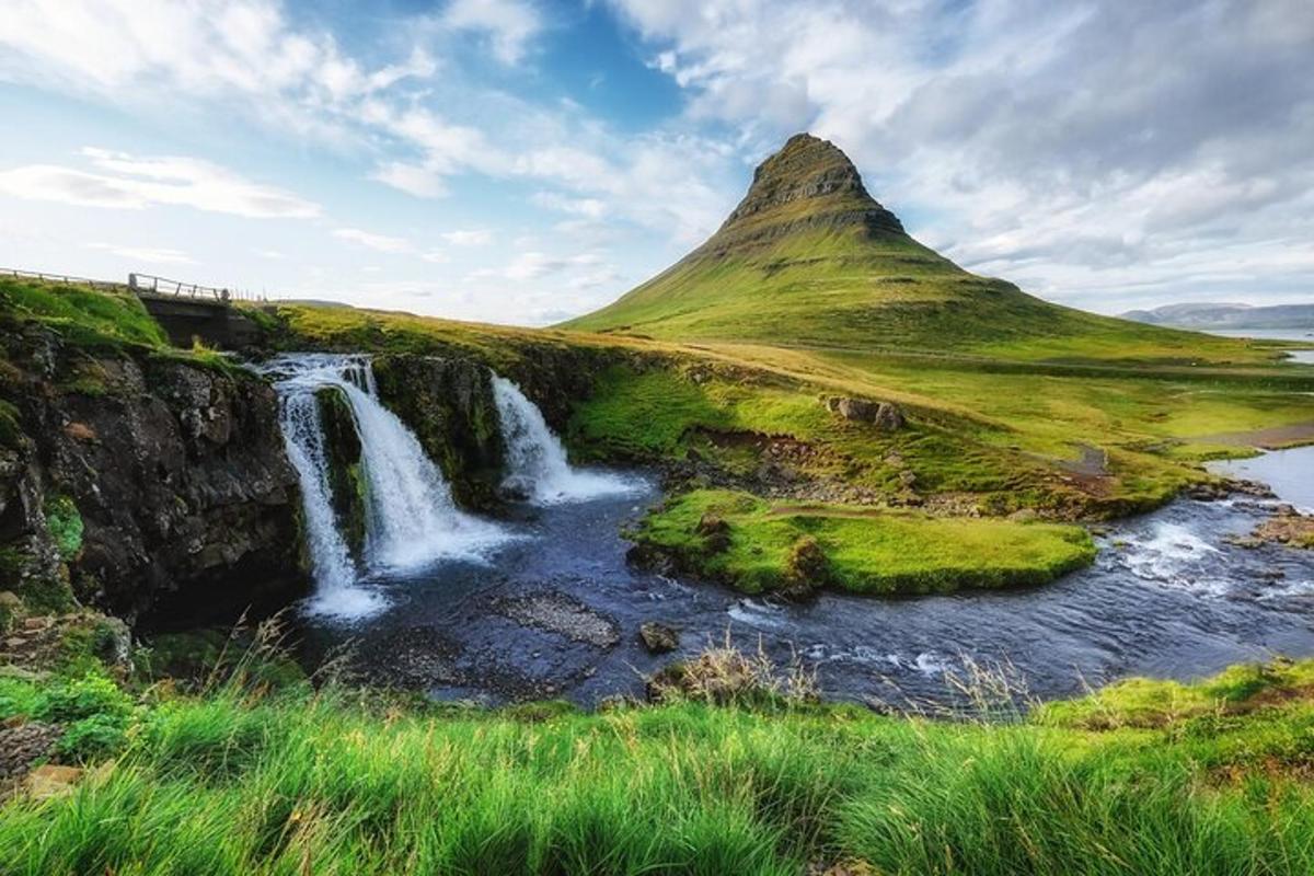 a waterfall in a field next to a mountain