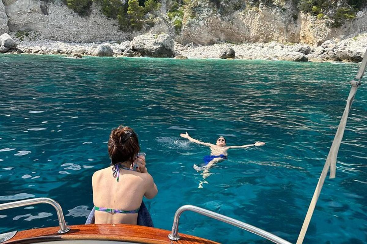ženska fotografira moškega v vodi na čolnu